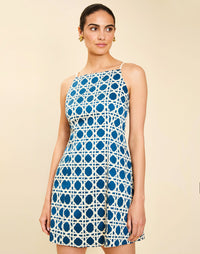 Woman wearing the Mestiza Havana Mini Dress in Solihiya Navy print, featuring a bib-neckline, bell skirt, removable belt, princess seaming, side seam pockets, and cotton poplin fabrication.