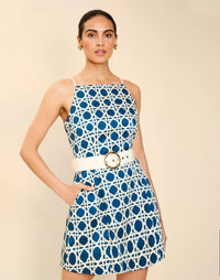 Woman wearing the Mestiza Havana Mini Dress in Solihiya Navy print, featuring a bib-neckline, bell skirt, removable belt, princess seaming, side seam pockets, and cotton poplin fabrication.