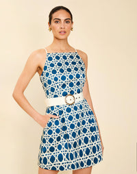 Woman wearing the Mestiza Havana Mini Dress in Solihiya Navy print, featuring a bib-neckline, bell skirt, removable belt, princess seaming, side seam pockets, and cotton poplin fabrication.