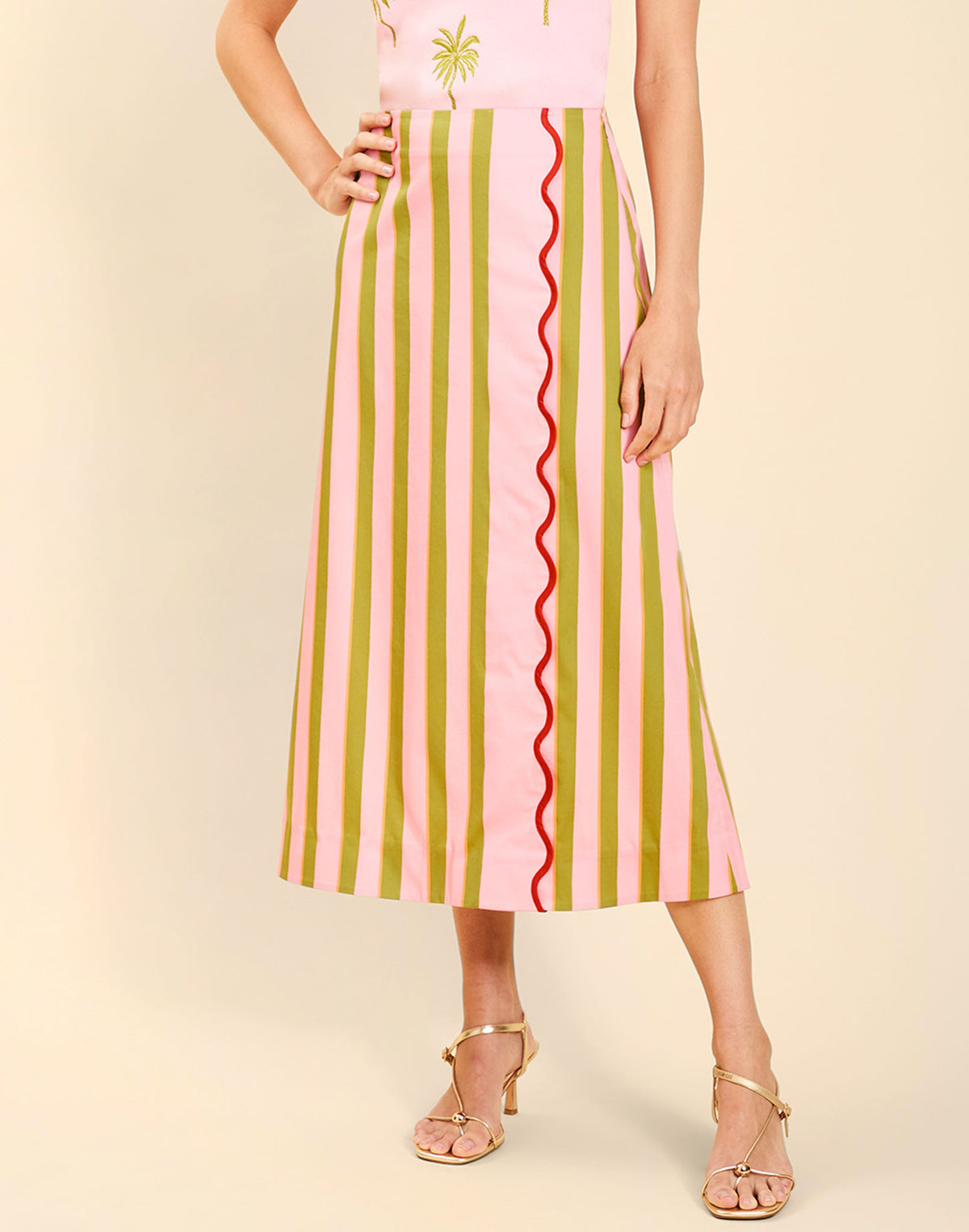 Woman wearing the Mestiza Joyah Midi Skirt in Herbes de Provence print, featuring a wrap-style silhouette, A-line shape, scalloped trim detailing, and cotton poplin fabrication.