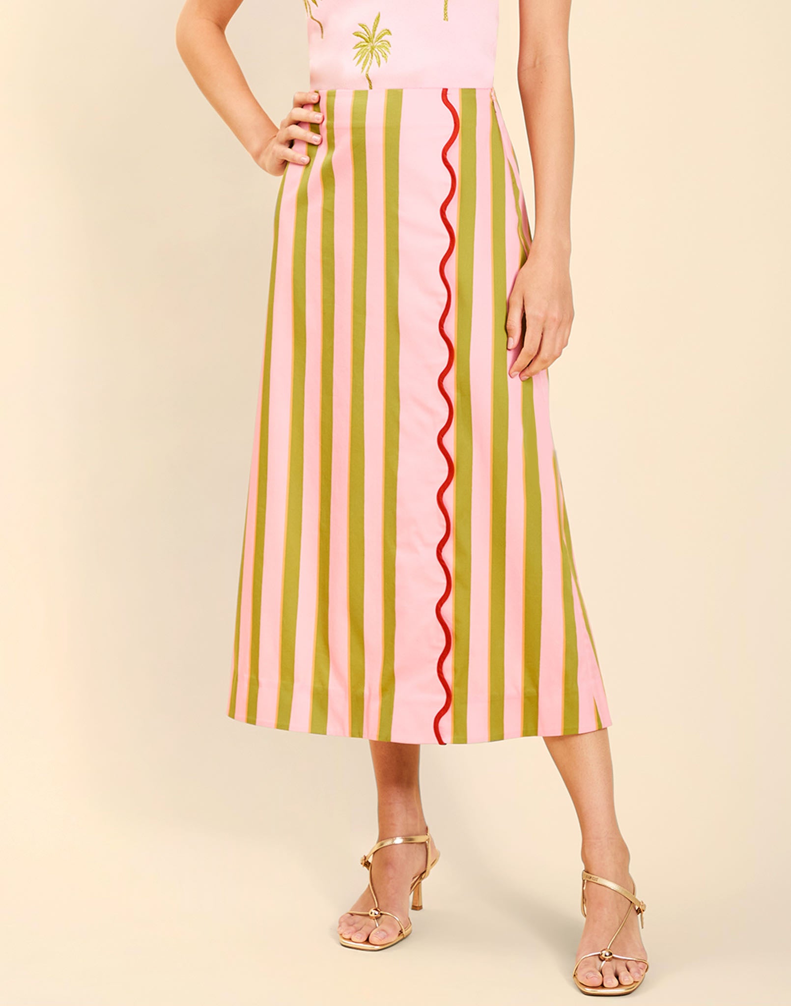 Woman wearing the Mestiza Joyah Midi Skirt in Herbes de Provence print, featuring a wrap-style silhouette, A-line shape, scalloped trim detailing, and cotton poplin fabrication.