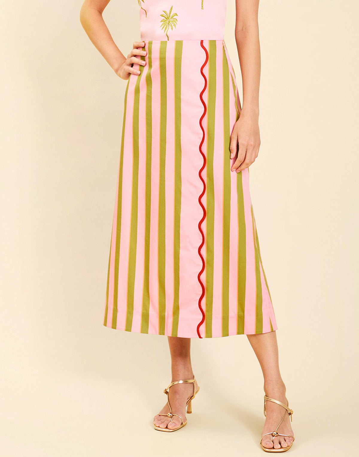 Woman wearing the Mestiza Joyah Midi Skirt in Herbes de Provence print, featuring a wrap-style silhouette, A-line shape, scalloped trim detailing, and cotton poplin fabrication.