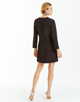 Black mini shift dress with sleeves, pockets, and sequined bow embellishments on front. 