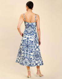 Woman wearing the Mestiza Ladera Midi Dress in Azulejo Navy print, featuring a fitted bodice, full A-line skirt, straight-across neckline, adjustable straps, side seam pockets, and linen organza fabrication.