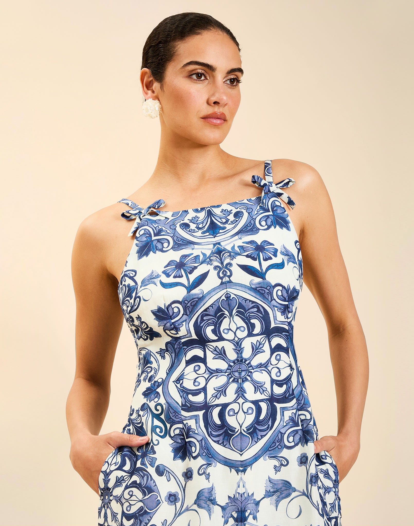 Woman wearing the Mestiza Ladera Midi Dress in Azulejo Navy print, featuring a fitted bodice, full A-line skirt, straight-across neckline, adjustable straps, side seam pockets, and linen organza fabrication.