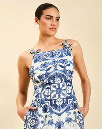 Woman wearing the Mestiza Ladera Midi Dress in Azulejo Navy print, featuring a fitted bodice, full A-line skirt, straight-across neckline, adjustable straps, side seam pockets, and linen organza fabrication.