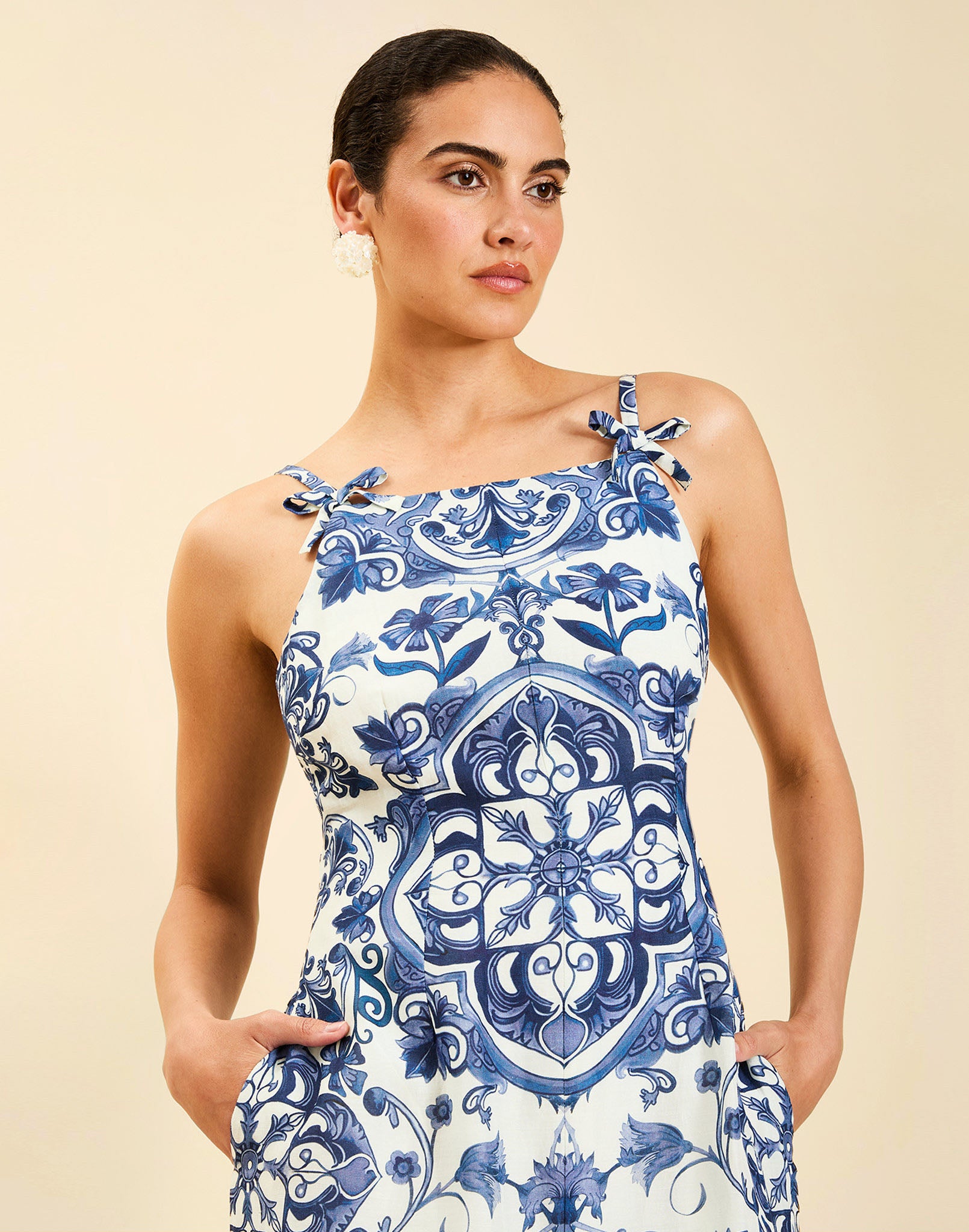 Woman wearing the Mestiza Ladera Midi Dress in Azulejo Navy print, featuring a fitted bodice, full A-line skirt, straight-across neckline, adjustable straps, side seam pockets, and linen organza fabrication.