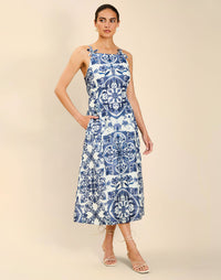 Woman wearing the Mestiza Ladera Midi Dress in Azulejo Navy print, featuring a fitted bodice, full A-line skirt, straight-across neckline, adjustable straps, side seam pockets, and linen organza fabrication.