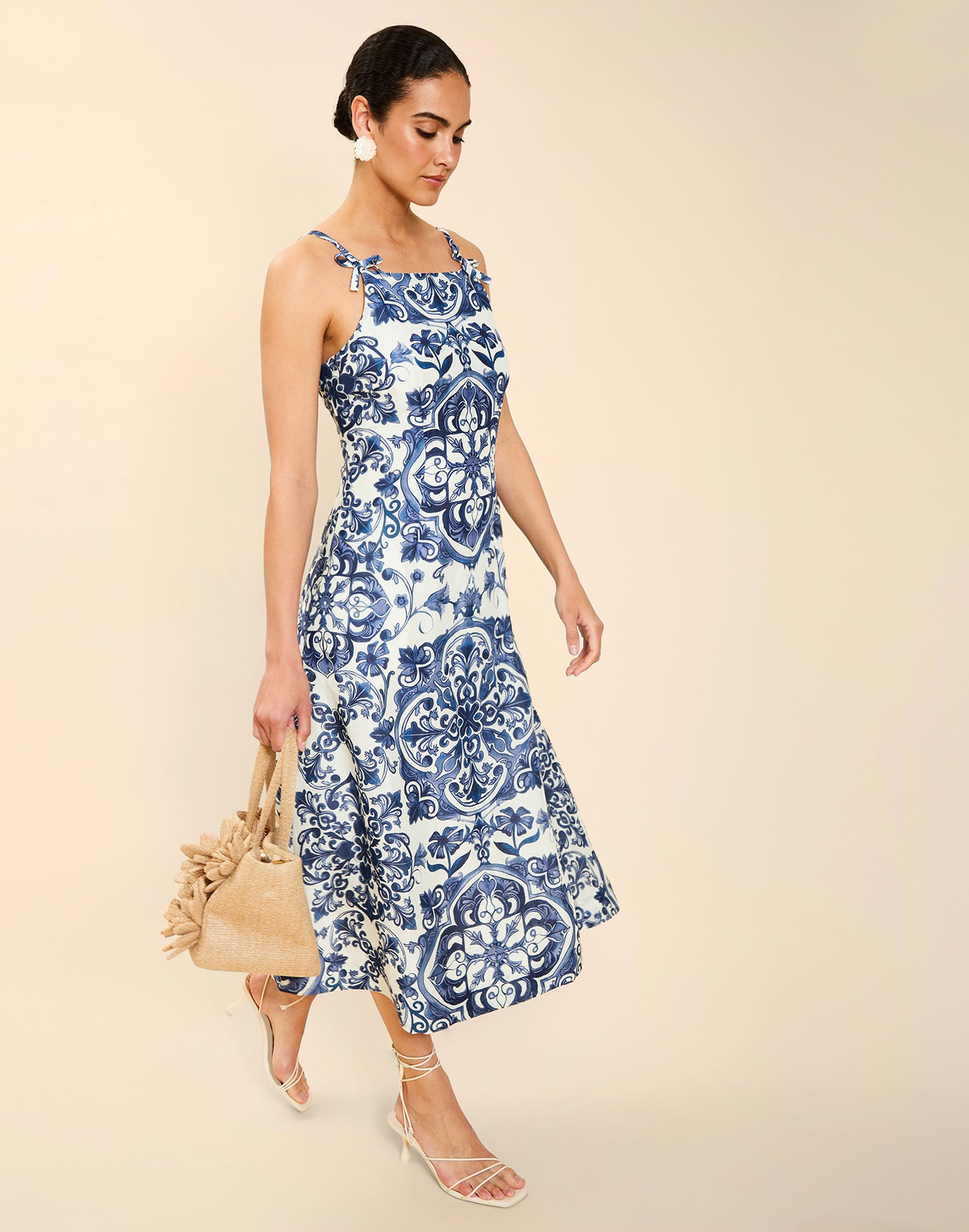 Woman wearing the Mestiza Ladera Midi Dress in Azulejo Navy print, featuring a fitted bodice, full A-line skirt, straight-across neckline, adjustable straps, side seam pockets, and linen organza fabrication.