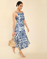 Woman wearing the Mestiza Ladera Midi Dress in Azulejo Navy print, featuring a fitted bodice, full A-line skirt, straight-across neckline, adjustable straps, side seam pockets, and linen organza fabrication.