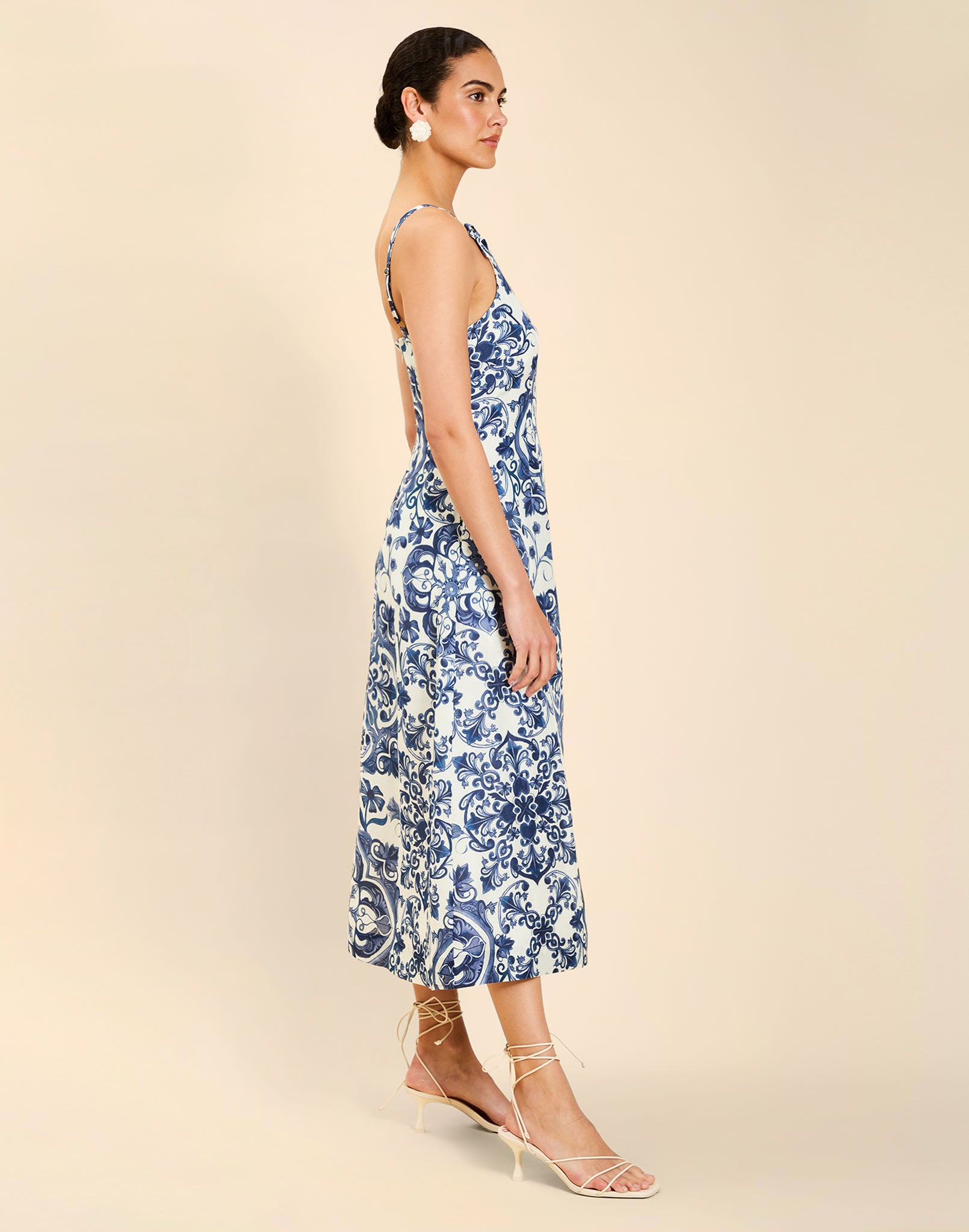 Woman wearing the Mestiza Ladera Midi Dress in Azulejo Navy print, featuring a fitted bodice, full A-line skirt, straight-across neckline, adjustable straps, side seam pockets, and linen organza fabrication.