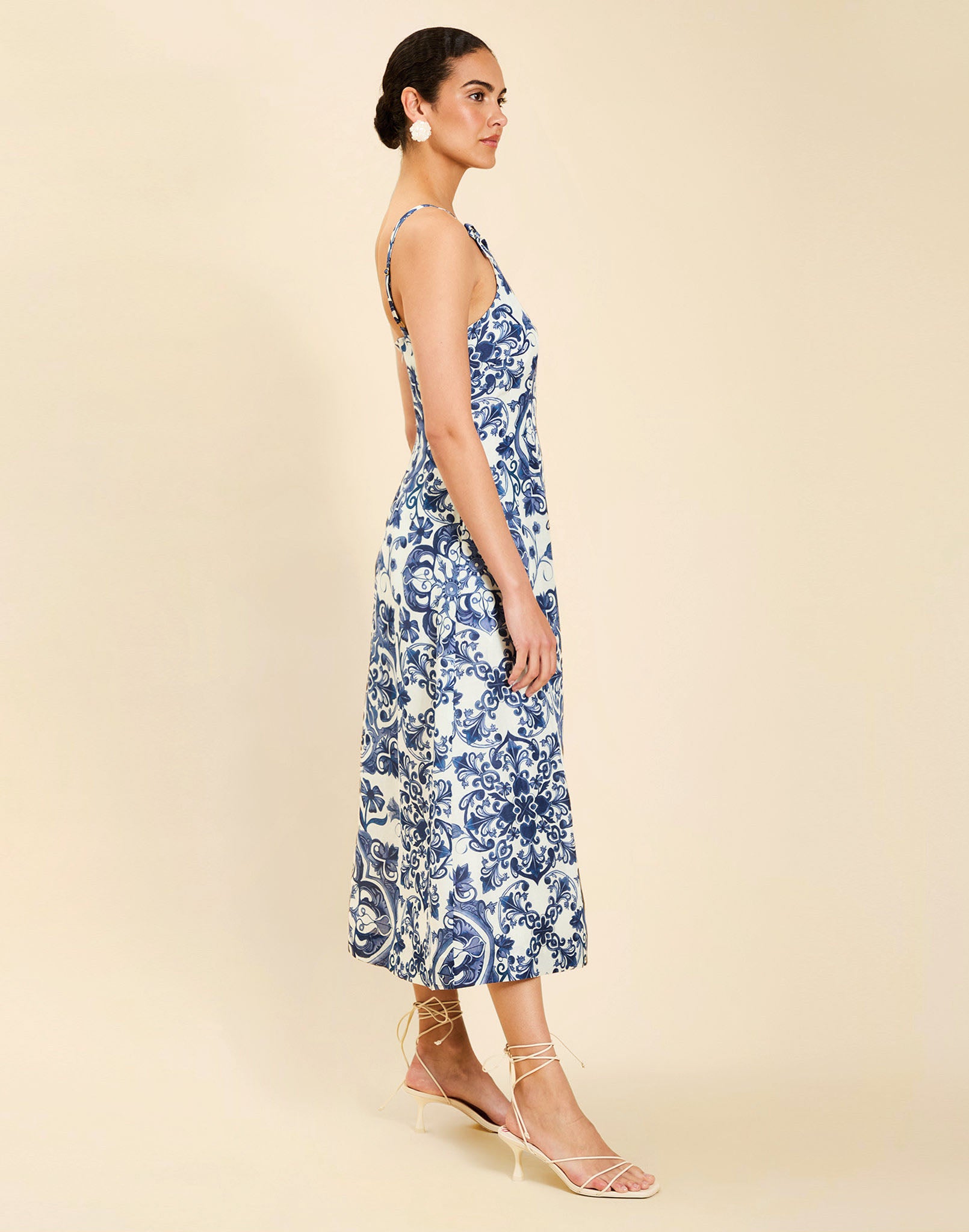 Woman wearing the Mestiza Ladera Midi Dress in Azulejo Navy print, featuring a fitted bodice, full A-line skirt, straight-across neckline, adjustable straps, side seam pockets, and linen organza fabrication.