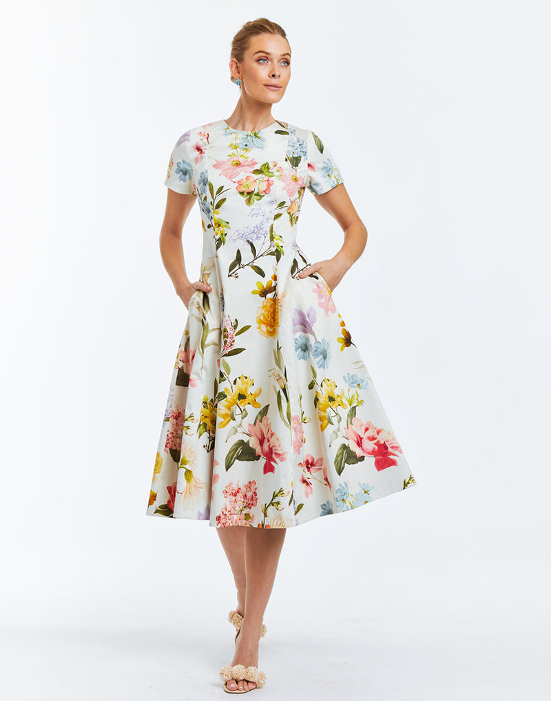 Convertible midi dress featuring one side with floral print on ivory background and a solid ocean blue fabric on opposing side. Crew neckline and fitted short sleeves along with a coordinating belt. 