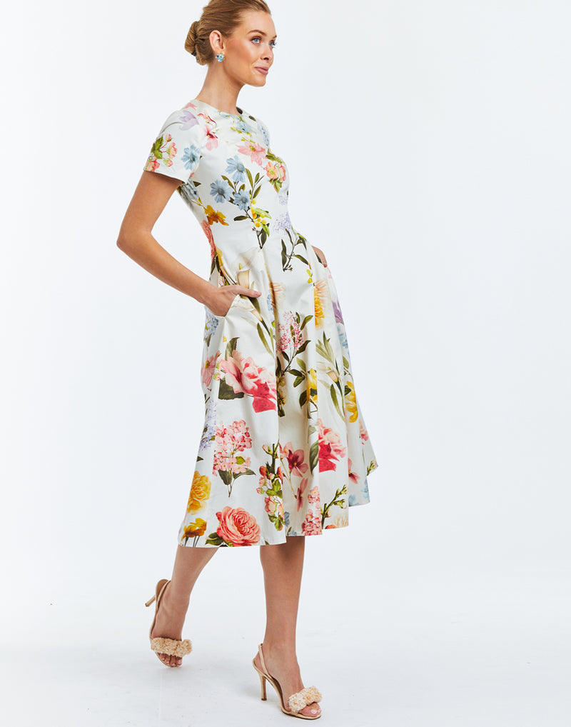 Convertible midi dress featuring one side with floral print on ivory background and a solid ocean blue fabric on opposing side. Crew neckline and fitted short sleeves along with a coordinating belt. 