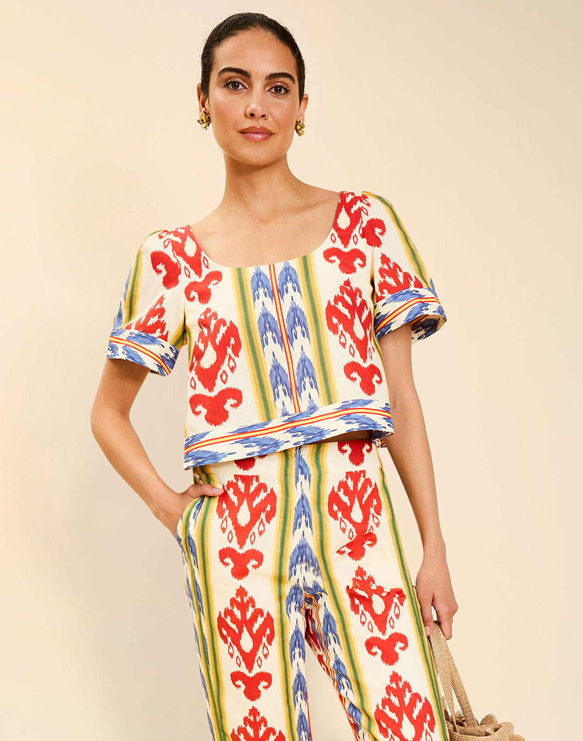 Woman wearing the Mestiza Maldives Top in Ikat Sunrise print, featuring a boxy silhouette, deep scoop neckline, pleated flutter sleeves, contrast ivory trim, and lightweight linen fabrication.