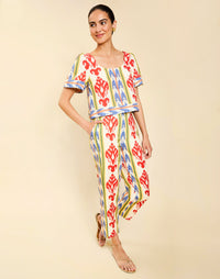 Woman wearing the Mestiza Maldives Top in Ikat Sunrise print, featuring a boxy silhouette, deep scoop neckline, pleated flutter sleeves, contrast ivory trim, and lightweight linen fabrication.