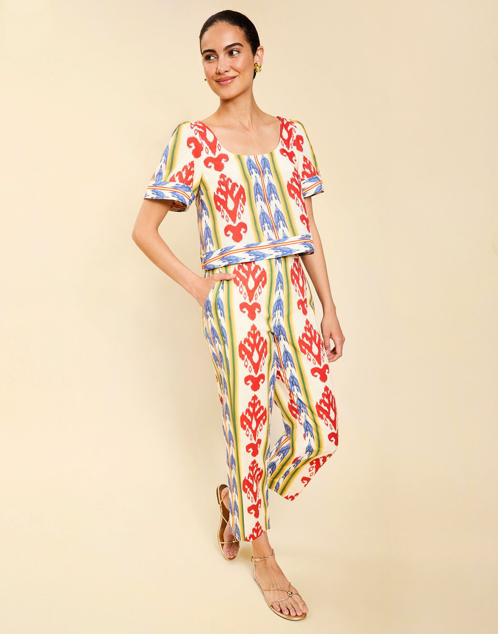 Woman wearing the Mestiza Maldives Top in Ikat Sunrise print, featuring a boxy silhouette, deep scoop neckline, pleated flutter sleeves, contrast ivory trim, and lightweight linen fabrication.