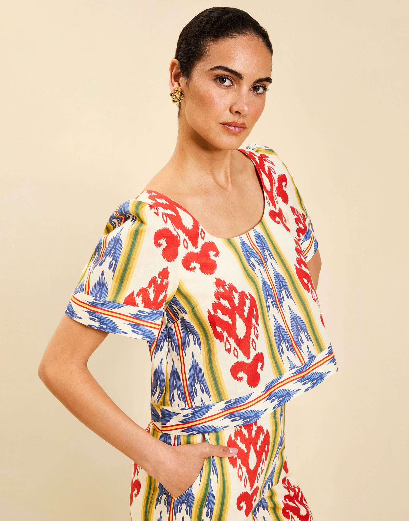 Woman wearing the Mestiza Maldives Top in Ikat Sunrise print, featuring a boxy silhouette, deep scoop neckline, pleated flutter sleeves, contrast ivory trim, and lightweight linen fabrication.
