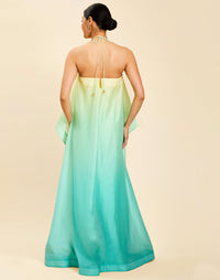 Woman wearing the Mestiza Mariposa Convertible Gown in Tuscan Sunrise print, featuring a column silhouette, removable cape overlay, racerback neckline, open back, self-tie halter straps, and linen organza fabrication.