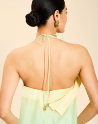 Woman wearing the Mestiza Mariposa Convertible Gown in Tuscan Sunrise print, featuring a column silhouette, removable cape overlay, racerback neckline, open back, self-tie halter straps, and linen organza fabrication.