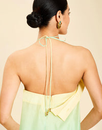 Woman wearing the Mestiza Mariposa Convertible Gown in Tuscan Sunrise print, featuring a column silhouette, removable cape overlay, racerback neckline, open back, self-tie halter straps, and linen organza fabrication.