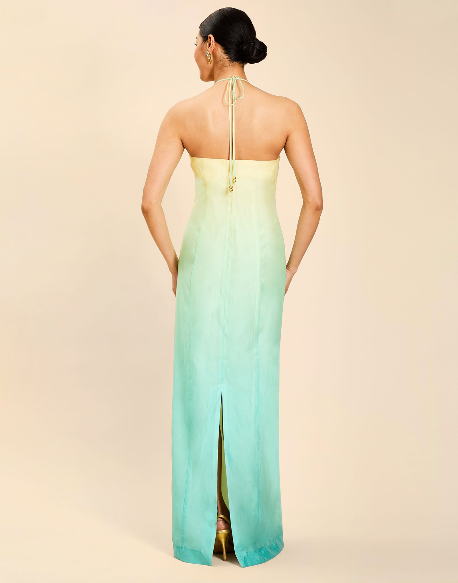 Woman wearing the Mestiza Mariposa Convertible Gown in Tuscan Sunrise print, featuring a column silhouette, removable cape overlay, racerback neckline, open back, self-tie halter straps, and linen organza fabrication.