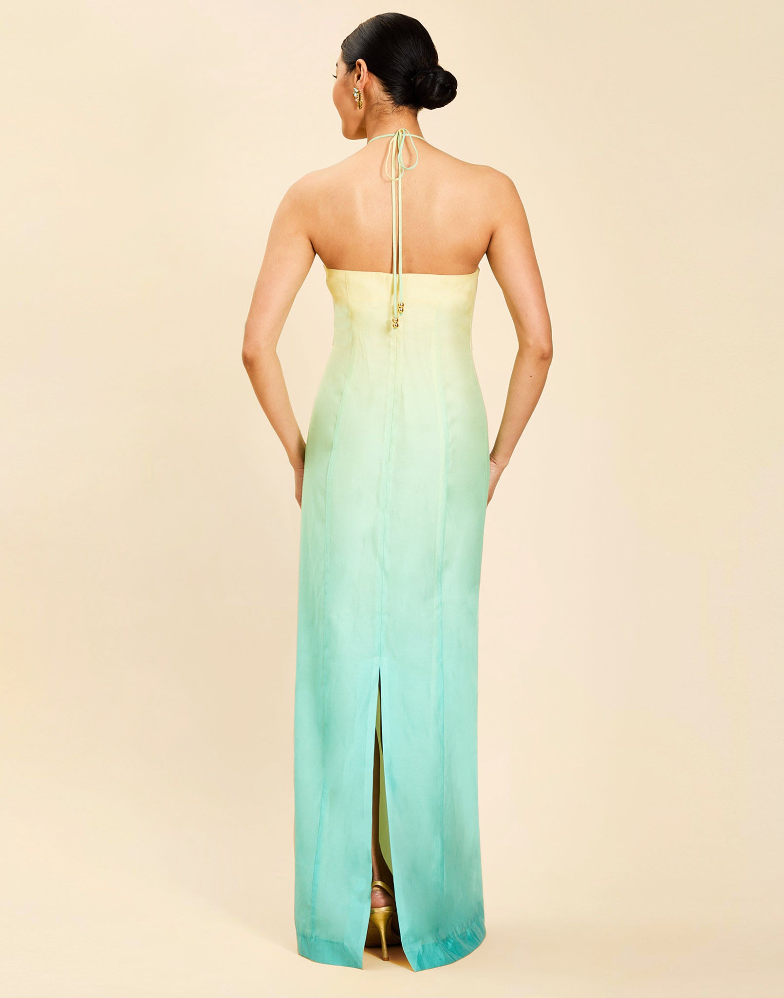 Woman wearing the Mestiza Mariposa Convertible Gown in Tuscan Sunrise print, featuring a column silhouette, removable cape overlay, racerback neckline, open back, self-tie halter straps, and linen organza fabrication.