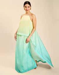 Woman wearing the Mestiza Mariposa Convertible Gown in Tuscan Sunrise print, featuring a column silhouette, removable cape overlay, racerback neckline, open back, self-tie halter straps, and linen organza fabrication.