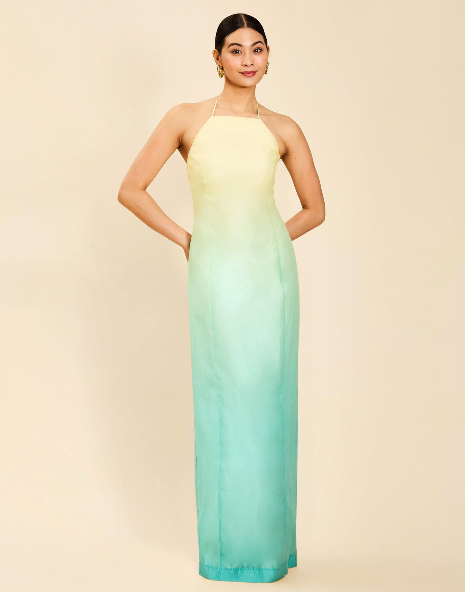 Woman wearing the Mestiza Mariposa Convertible Gown in Tuscan Sunrise print, featuring a column silhouette, removable cape overlay, racerback neckline, open back, self-tie halter straps, and linen organza fabrication.