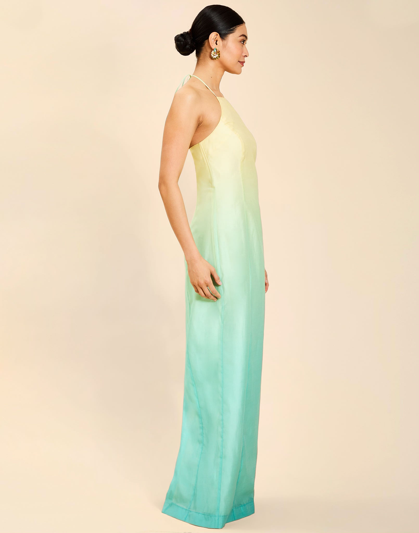 Woman wearing the Mestiza Mariposa Convertible Gown in Tuscan Sunrise print, featuring a column silhouette, removable cape overlay, racerback neckline, open back, self-tie halter straps, and linen organza fabrication.