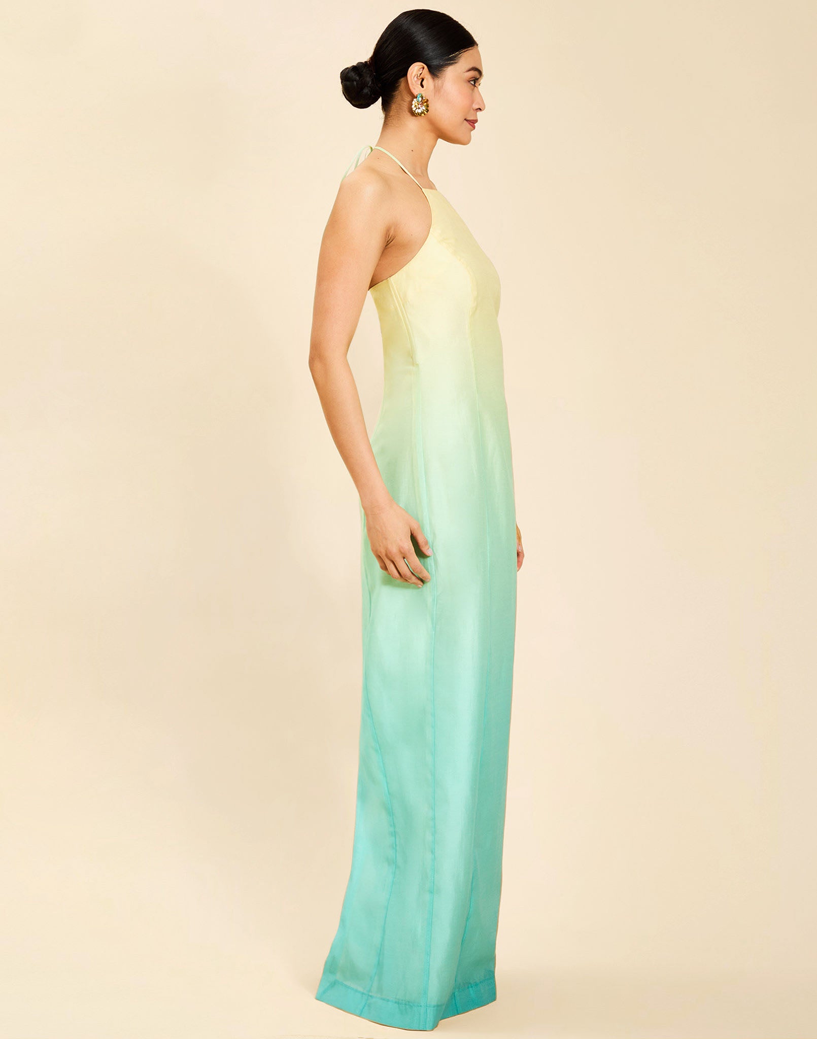 Woman wearing the Mestiza Mariposa Convertible Gown in Tuscan Sunrise print, featuring a column silhouette, removable cape overlay, racerback neckline, open back, self-tie halter straps, and linen organza fabrication.