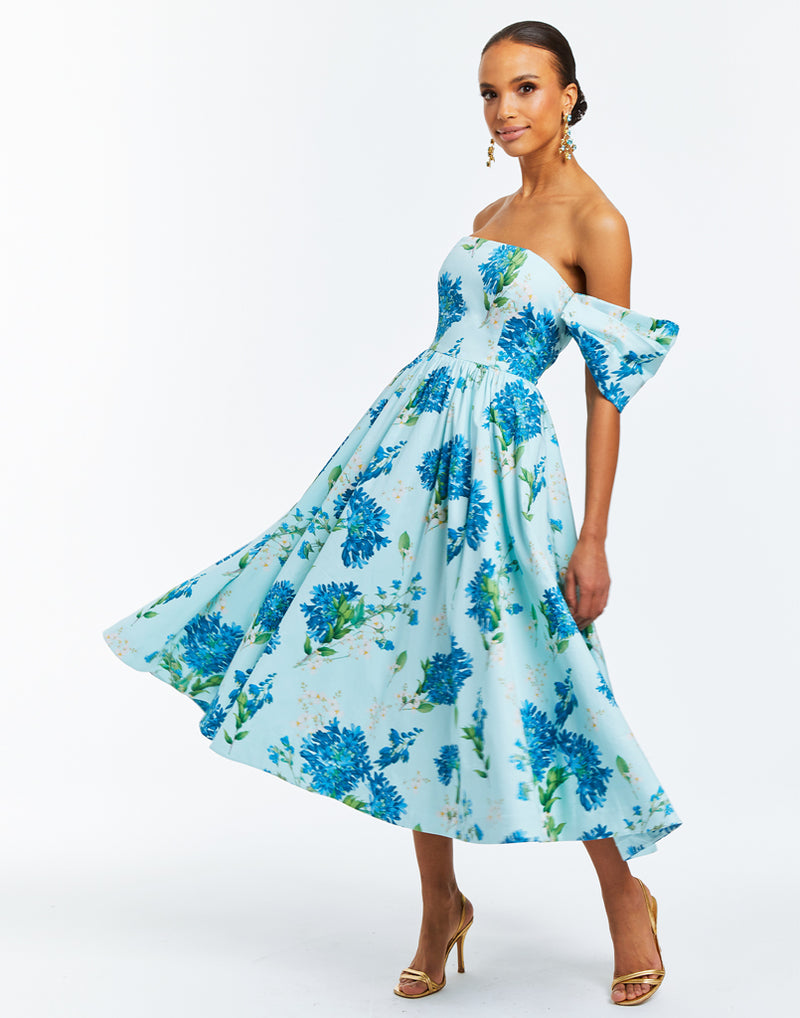 Blue midi dress with floral print. On or off-the-shoulder straps, boning in bodice and pockets at side seams. 