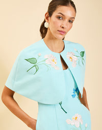 Promenade Embroidered Capelet in Blue Waltz moire with hand-sewn floral embroidery, crew neckline, and hook-and-eye closure.