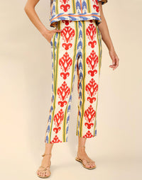 Woman wearing the Mestiza Palau Cigarette Pant in Ikat Sunrise print, featuring a slim-fit cigarette silhouette, front pleat detailing, cropped ankle-length fit, and lightweight linen fabrication.