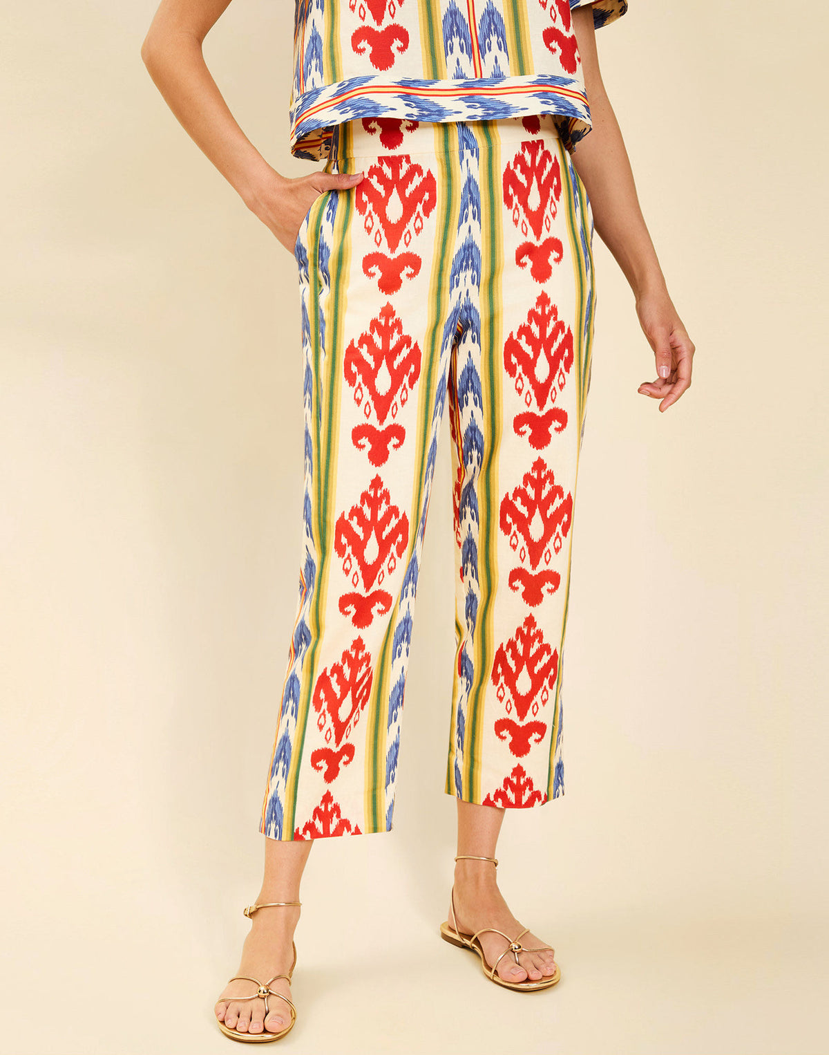 Woman wearing the Mestiza Palau Cigarette Pant in Ikat Sunrise print, featuring a slim-fit cigarette silhouette, front pleat detailing, cropped ankle-length fit, and lightweight linen fabrication.