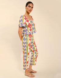 Woman wearing the Mestiza Palau Cigarette Pant in Ikat Sunrise print, featuring a slim-fit cigarette silhouette, front pleat detailing, cropped ankle-length fit, and lightweight linen fabrication.