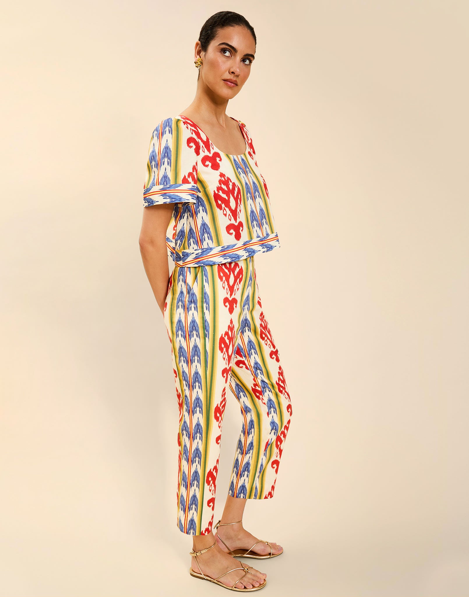 Woman wearing the Mestiza Palau Cigarette Pant in Ikat Sunrise print, featuring a slim-fit cigarette silhouette, front pleat detailing, cropped ankle-length fit, and lightweight linen fabrication.