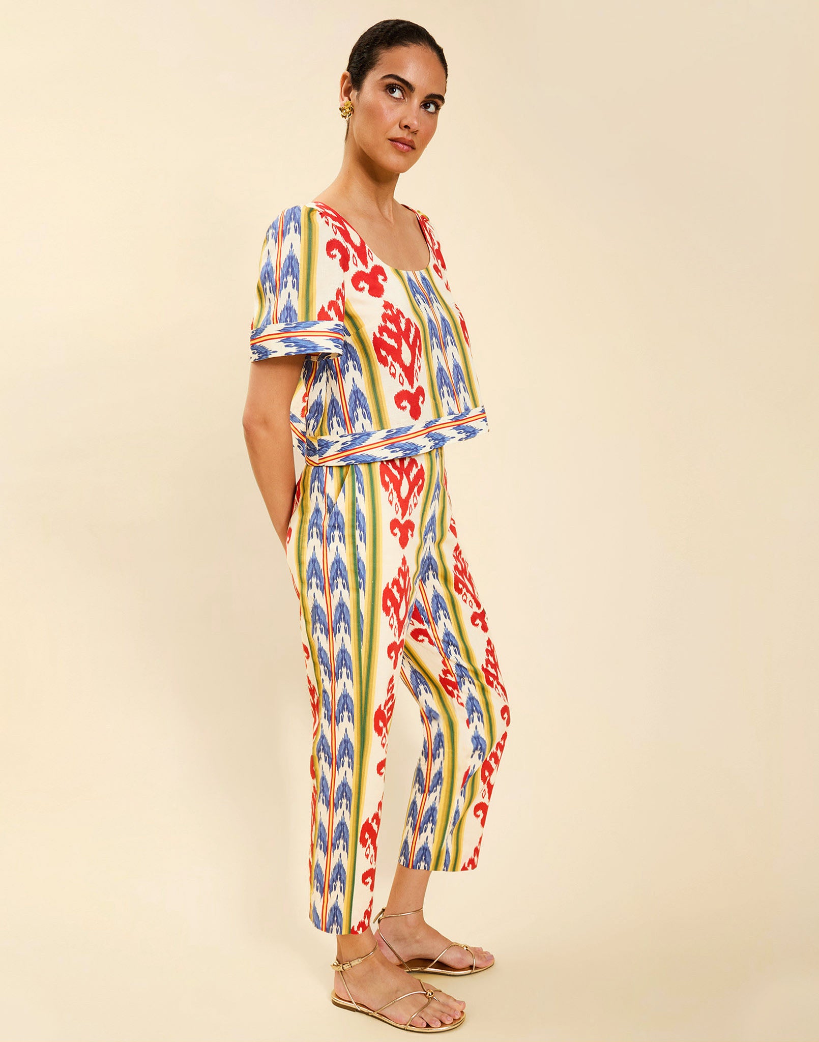 Woman wearing the Mestiza Palau Cigarette Pant in Ikat Sunrise print, featuring a slim-fit cigarette silhouette, front pleat detailing, cropped ankle-length fit, and lightweight linen fabrication.