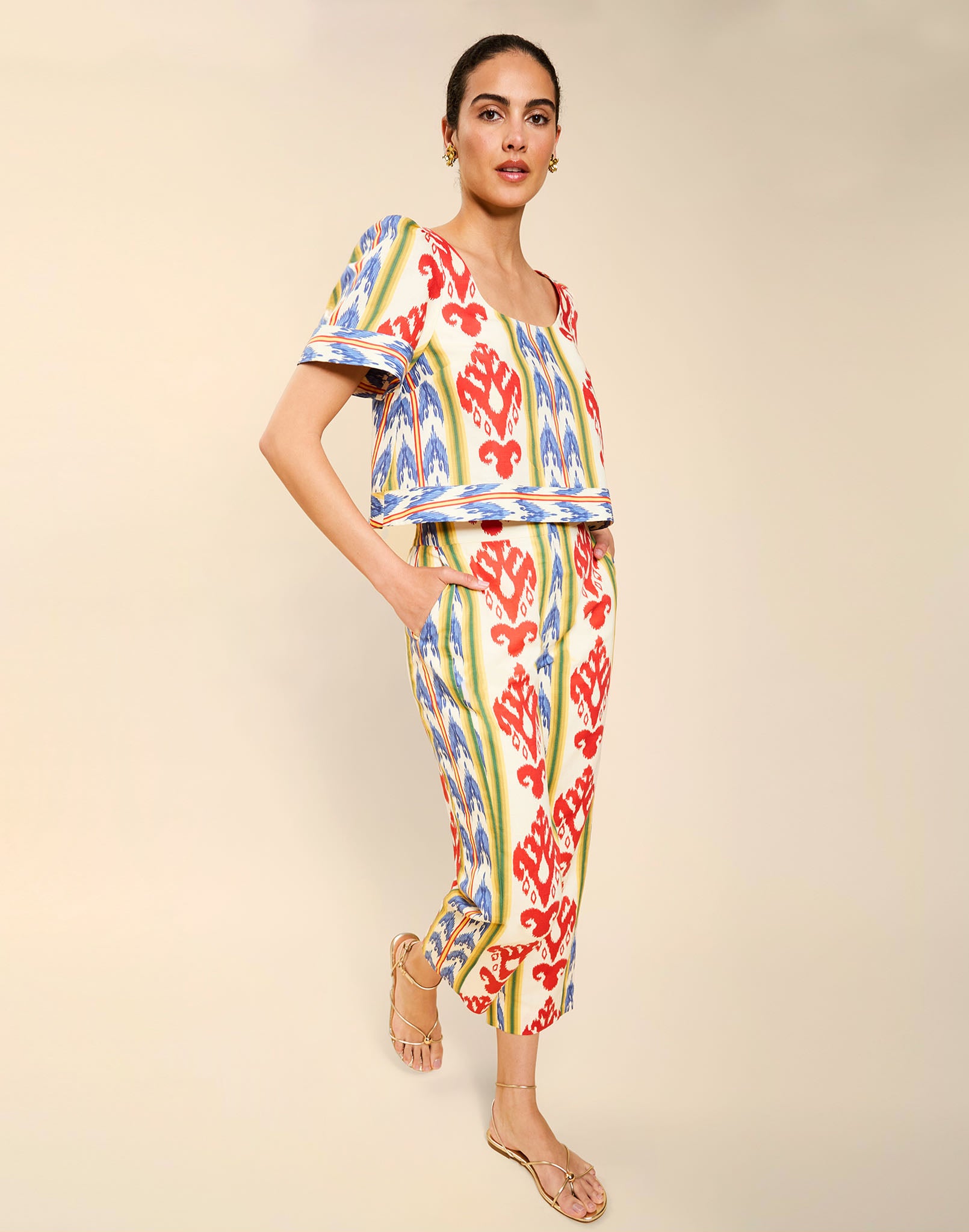 Woman wearing the Mestiza Palau Cigarette Pant in Ikat Sunrise print, featuring a slim-fit cigarette silhouette, front pleat detailing, cropped ankle-length fit, and lightweight linen fabrication.