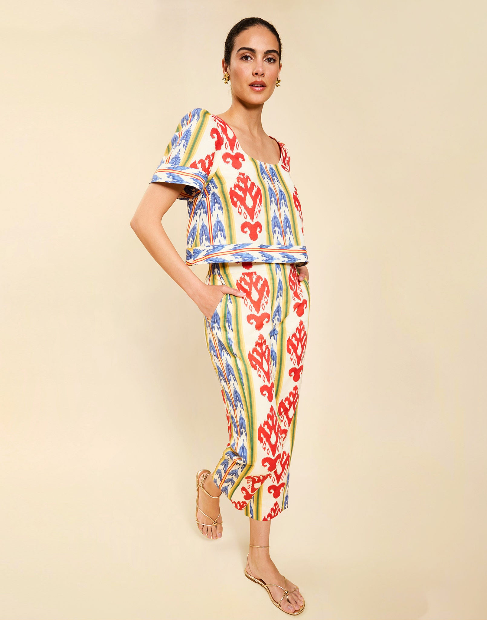 Woman wearing the Mestiza Palau Cigarette Pant in Ikat Sunrise print, featuring a slim-fit cigarette silhouette, front pleat detailing, cropped ankle-length fit, and lightweight linen fabrication.