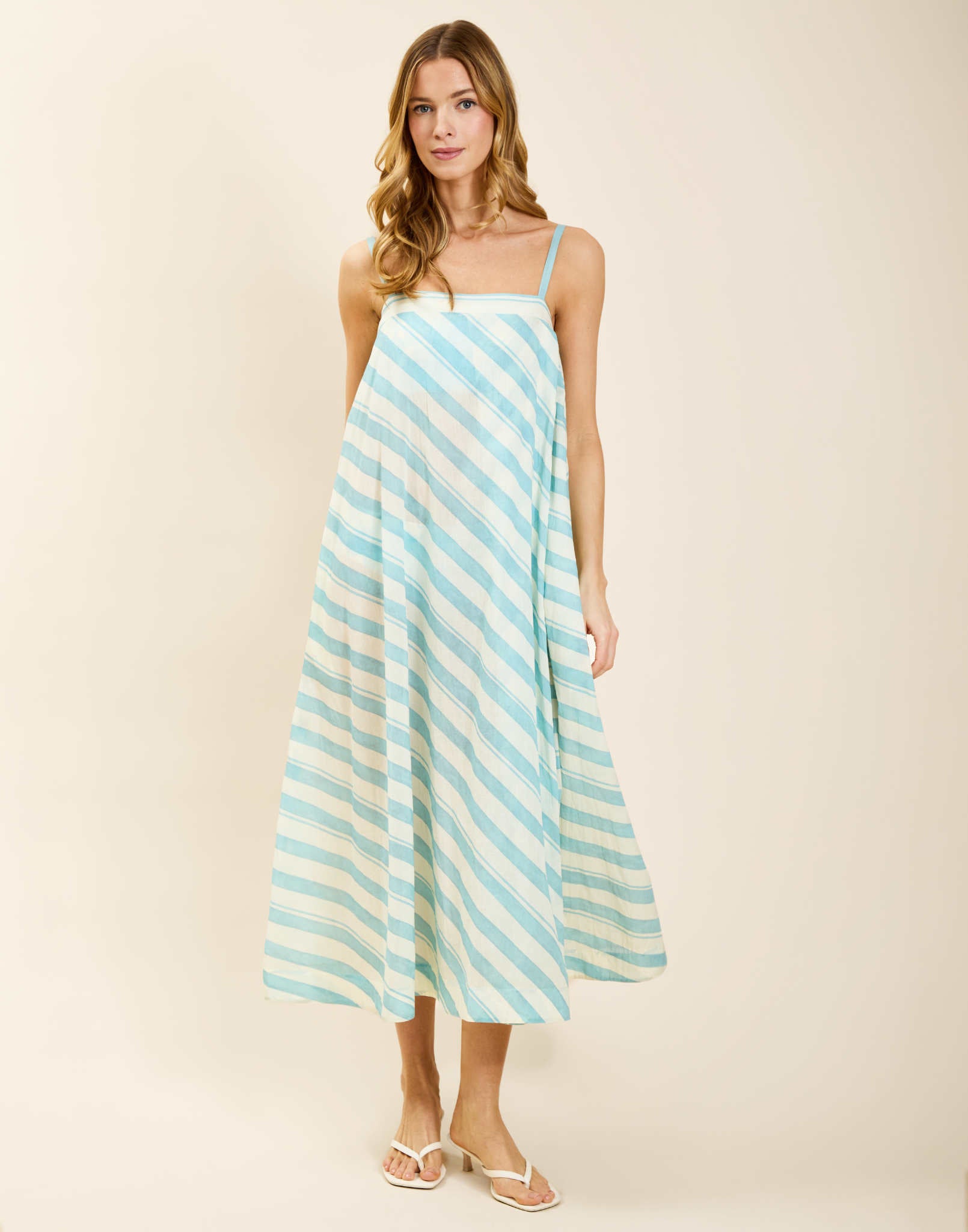 Model wearing Portofino Maxi Dress in Aegean Stripe cotton voile with straight neckline and flared silhouette.