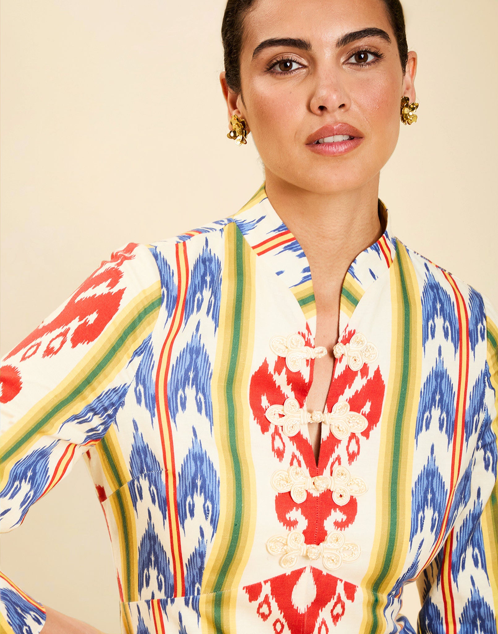 Woman wearing the Mestiza Shoshi Midi Dress in Ikat Sunrise print, featuring a fitted bodice, A-line midi skirt, mandarin collar, functional frog tie closures, side seam pockets, and linen fabrication.