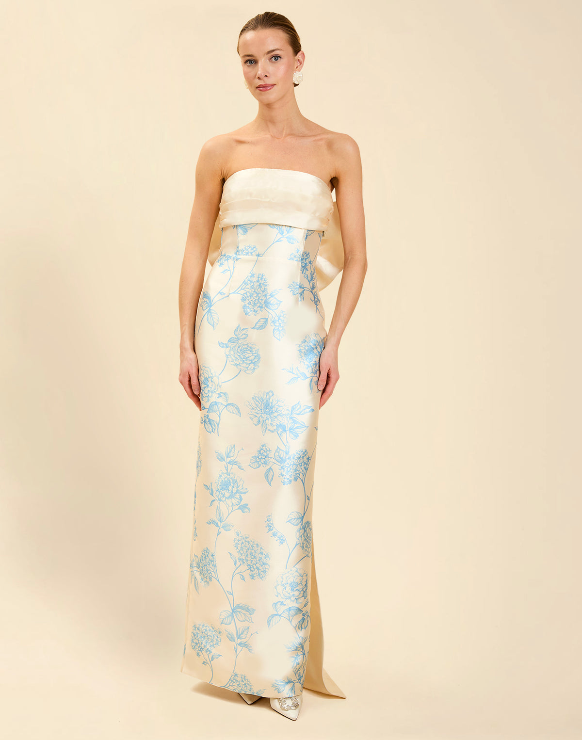 Solstice Gown in Powder Batiste poly silk twill with strapless neckline, removable pleated band, statement bow detail, and fitted gown silhouette.