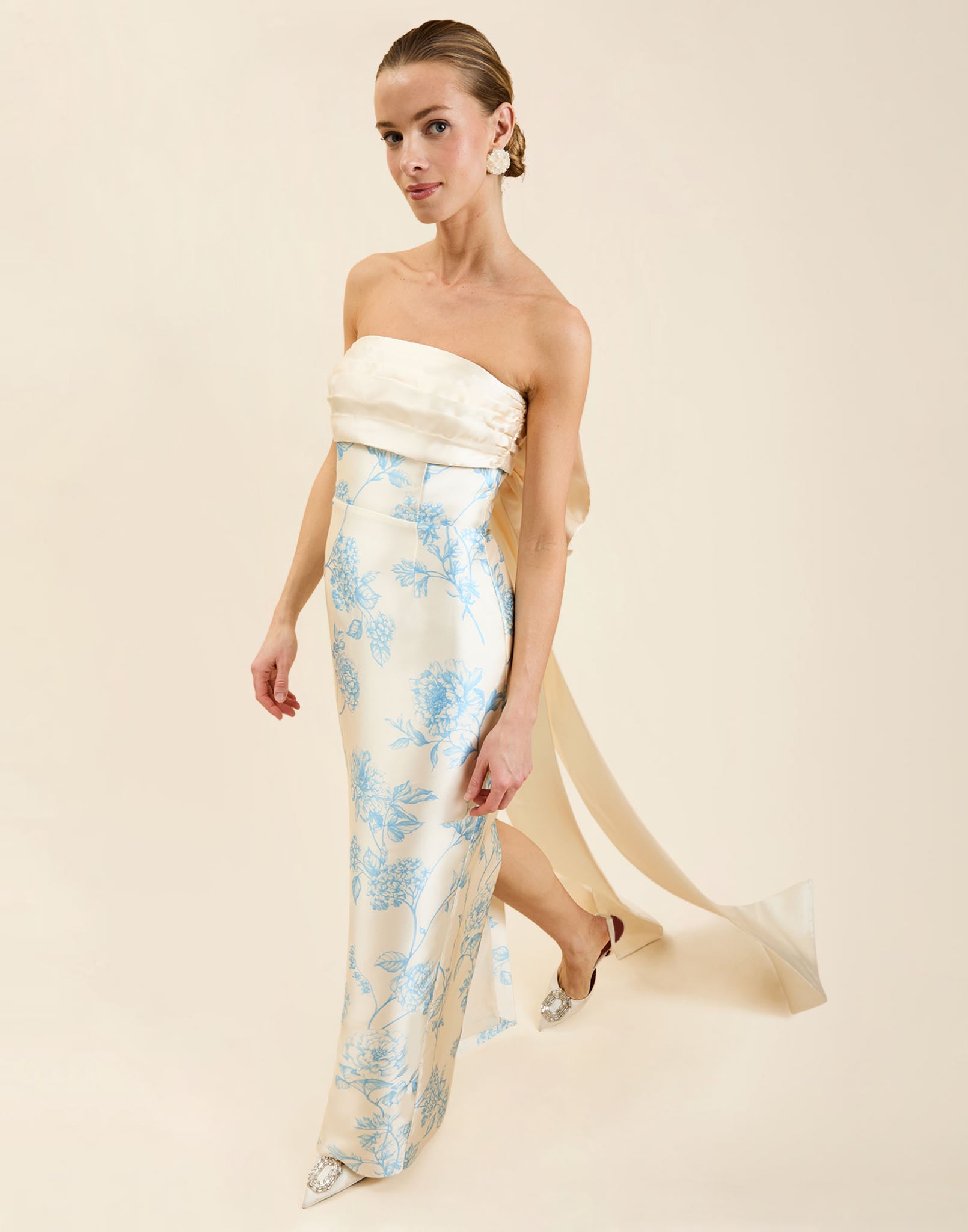 Solstice Gown in Powder Batiste poly silk twill with strapless neckline, removable pleated band, statement bow detail, and fitted gown silhouette.
