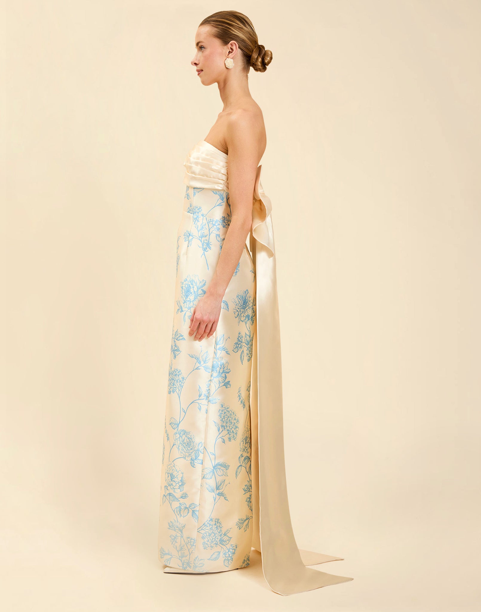 Solstice Gown in Powder Batiste poly silk twill with strapless neckline, removable pleated band, statement bow detail, and fitted gown silhouette.