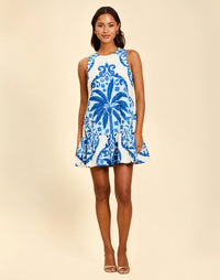 Model wearing the Sorella Mini Dress in Mediterranean Mist, a sleeveless linen mini dress with an A-line silhouette, ruffle hem, and side pockets.
