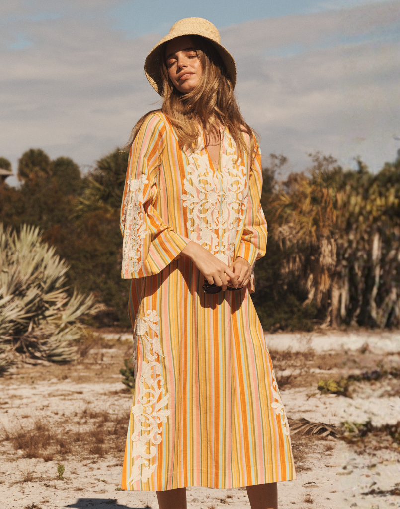 Ines Midi Caftan in Sunset Ribbons linen with embroidery detail, djellaba collar, bell sleeves, and column silhouette.