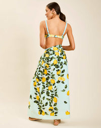 Model wearing Isla Sarong in Sorrento Citrus cotton poplin with contrast border tied at waist over swimwear.