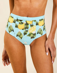 Model wearing Matera High-Waist Bikini Bottom in Sorrento Citrus with bow detail and full back coverage.